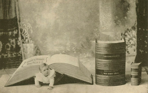 Baby crawling from underneath a very large book.