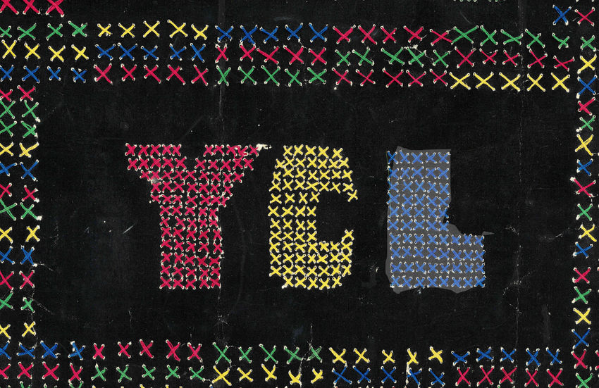 YCL scrapbook cover made with red, yellow, and blue cross-stitch.